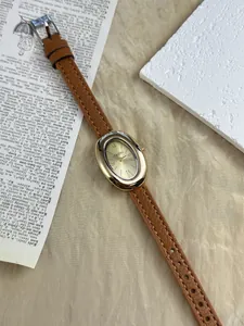 Gedetailleerd zicht op vintage gouden ovaal horloge met chique bruine leren band