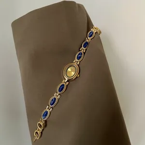 Détail d'une montre-bracelet dorée de luxe vintage avec des pierres bleues élégantes