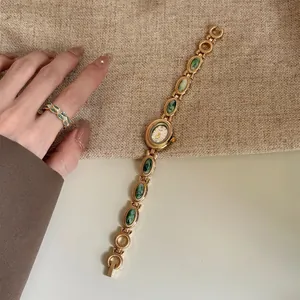 Vue détaillée d'une montre-bracelet dorée vintage avec pierres vertes et bague
