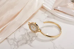 Elegante orologio a bracciale dorato da donna con quadrante di strass su marmo