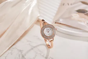 Dettaglio orologio a bracciale in oro rosa con lunetta di cristalli e quadrante bianco