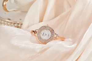 Elegante orologio da polso da donna in oro rosa con lunetta in strass su fondo di seta