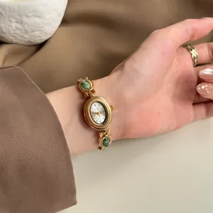 Gros plan d'une montre bracelet dorée vintage avec des pierres précieuses vertes