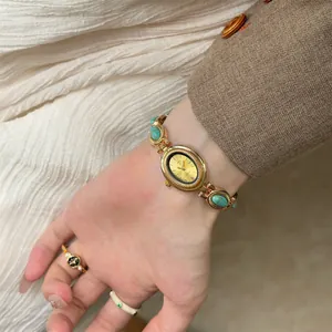 Vue détaillée d'une montre bracelet vintage en or avec pierres turquoises au poignet
