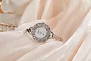 Dettaglio di un orologio a bracciale da donna in argento con strass su seta di lusso.