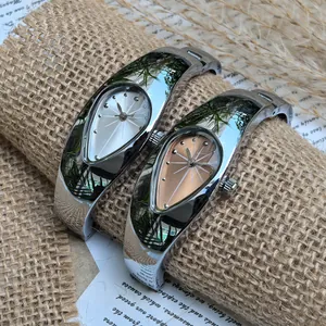 Gros plan sur des montres joncs argentées en forme de goutte Y2K sur un fond vintage