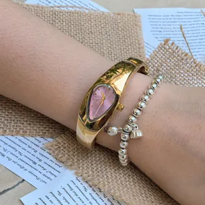 Vue détaillée d'une montre dorée Y2K en forme de larme et d'un bracelet à breloques argenté