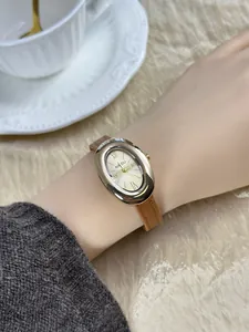 Elegant detailshot van een vintage ovaal goud horloge met bruine leren band om een pols.