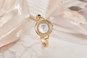 Primo piano di un orologio a bracciale da donna in oro con quadrante in madreperla