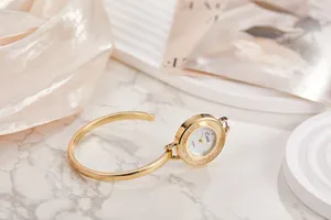 Dettaglio di elegante orologio a bracciale dorato con quadrante incrostato di cristalli
