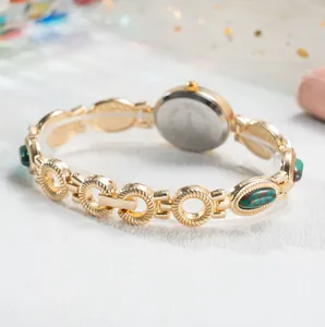 Élégante montre-bracelet vintage dorée pour femme avec détails en pierres vertes luxe