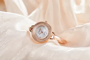 Dettaglio dell'orologio rigido oro rosa con cristalli e quadrante bianco su tessuto