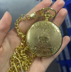 Gros plan d'une montre à gousset mécanique dorée vintage avec gravures florales et chaîne