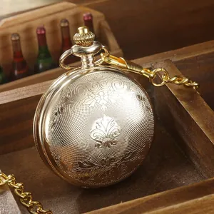 Détail d'une montre de poche dorée vintage avec gravures florales complexes et chaîne assortie