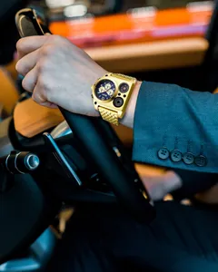 Gros plan de la montre dorée Oulm multi-fuseaux horaires portée dans une voiture
