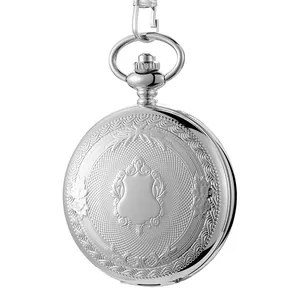 Gros plan détaillé d'une montre à gousset vintage argentée à gravure florale.