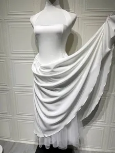 Detailweergave van elegante witte avondjurk met gedrapeerd satijn en tule zoom