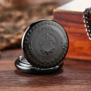 Gros plan d'une montre de poche vintage noire gravée sur un fond en bois rustique