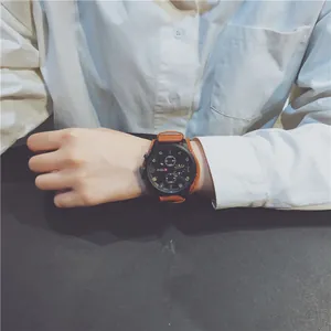 Close-up of a men's large black dial sport watch with a brown leather strap worn on wrist.