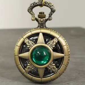 Primer plano de un reloj de bolsillo vintage de bronce con una gema de estrella verde central.