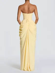 Elegant pale yellow strapless evening gown featuring a corset back and pleated draping