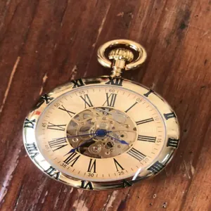 Gros plan d'une montre à gousset mécanique dorée vintage avec chiffres romains et cadran squelette