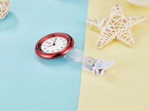 Macro view of a red quartz nurse watch focusing on the white dial and secure clip attachment
