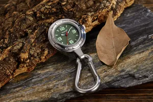 Detailaufnahme einer silbernen Karabineruhr mit grünem Zifferblatt auf Naturstein.