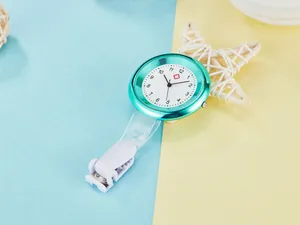 Detailed view of a stylish teal quartz nurse fob watch with clip on two-tone background