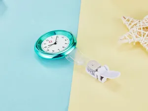 Detail view of a teal fashion quartz nurse watch with a white dial and clip attachment.