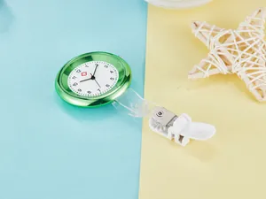 Close-up of a green quartz nurse watch with a clip on a blue and yellow background