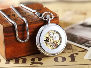 Gros plan d'une montre de poche mécanique vintage avec boîtier argenté et cadran squelette.