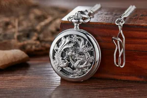 Gros plan d'une montre de poche mécanique vintage en argent avec gravure de dragon