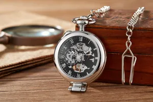 Gros plan d'une montre à gousset mécanique argentée posée sur une boîte en bois