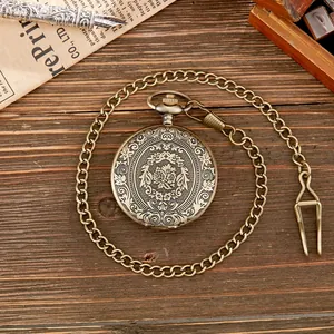 Montre à gousset vintage en bronze gravé avec motif floral sur un bureau en bois rustique