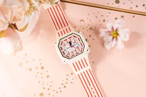 Primo piano di un orologio bianco a strisce rosse con quadrante ottagonale su sfondo rosa