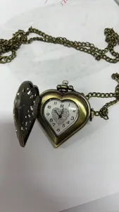 Detail van een vintage hartvormig bronzen zakhorloge met een glinsterende wijzerplaat.