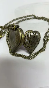 Detailweergave van een antiek bronzen hartvormig zakhorloge medaillon met gravure.