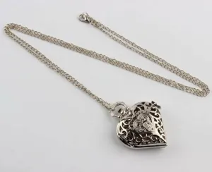 Close-up van een zilveren hartvormige zakhorloge ketting met filigraan patroon.