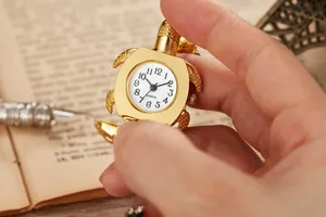 Detaillierte Makroansicht einer goldenen Vintage-Schildkröten-Taschenuhr als Schlüsselanhänger.