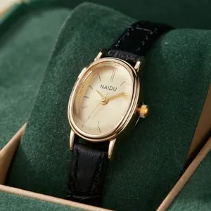 Élégante montre dorée ovale pour femme avec bracelet en cuir noir sur velours vert