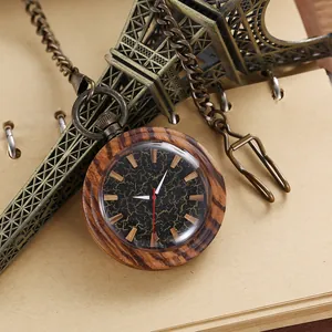 Close-up of a vintage wooden quartz pocket watch with a bronze chain on a notebook.