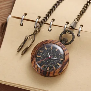 Detailed view of a vintage wooden pocket watch with a bronze chain on a notebook