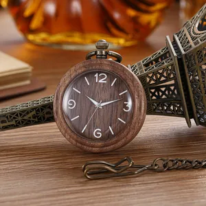 Close-up of a vintage wooden quartz pocket watch with a bronze chain on a wooden desk.