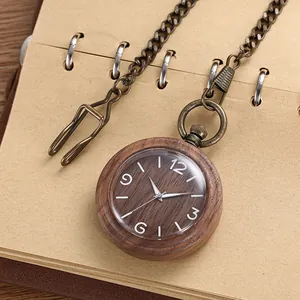 Close-up of vintage wooden pocket watch with bronze chain on a brown kraft notebook