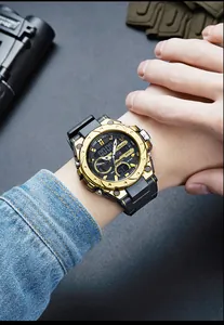 Detailed shot of gold SMAEL tactical sports watch worn on wrist in outdoor setting.