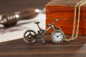 Nahaufnahme einer antiken bronzenen Quarztaschenuhr in Fahrradform auf Holzgrundlage