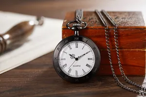 Macro detail of a vintage black quartz pocket watch featuring Roman numerals