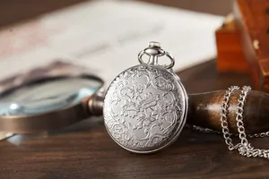 Detailed view of a vintage silver flip-top pocket watch with floral relief engraving.