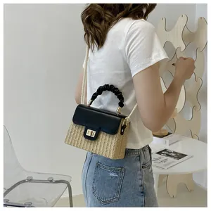 Nahaufnahme einer Stroh-Box-Tasche mit schwarzem gerafftem Griff und Goldverschluss
